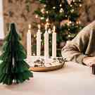 Gothaer Ratgeber: Vier brennende Kerzen stehen auf dem Tisch. Im Hintergrund ist ein Weihnachtsbaum.
